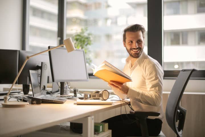 A happy worker sitting at a tidy desk is productive.
